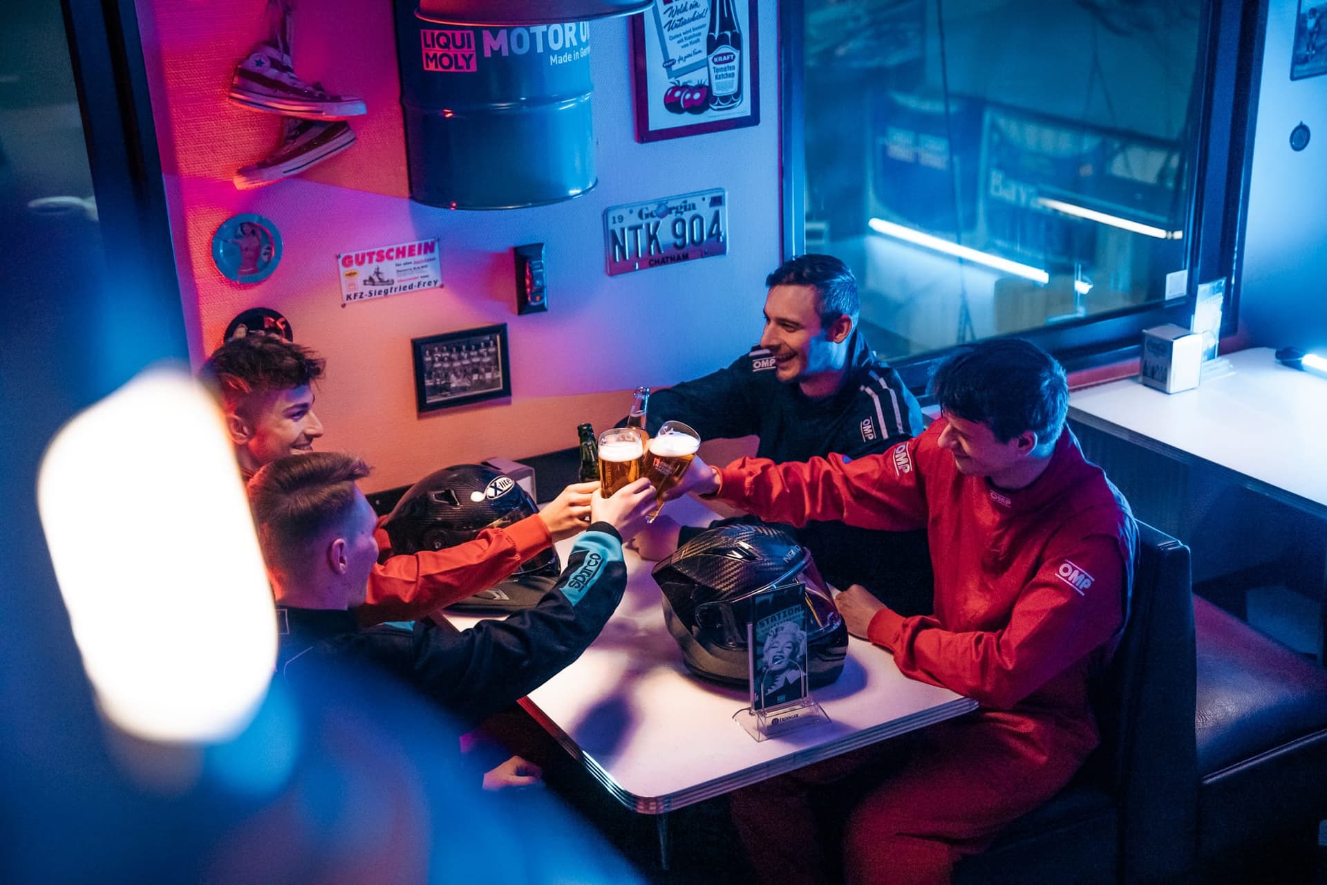 Team in Rennanzügen stößt im Bistro von Bavaria Kart an