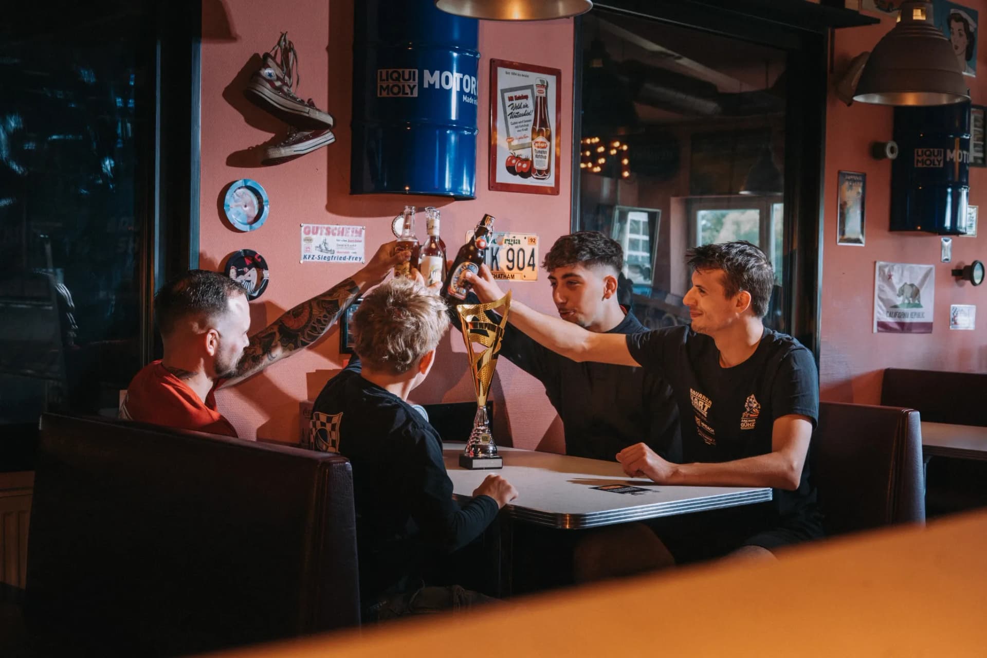 Fahrer stoßen nach dem Rennen im Bistro mit dem Pokal auf dem Tisch an